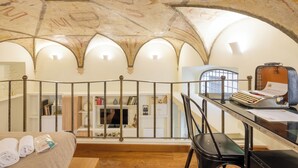 A room with a high arched ceiling, a balcony with a metal railing, a desk with a typewriter, and a bed with neatly folded towels. - Piazza Navona - Apartment with Authentic Fresco of the 1500s (Roma)