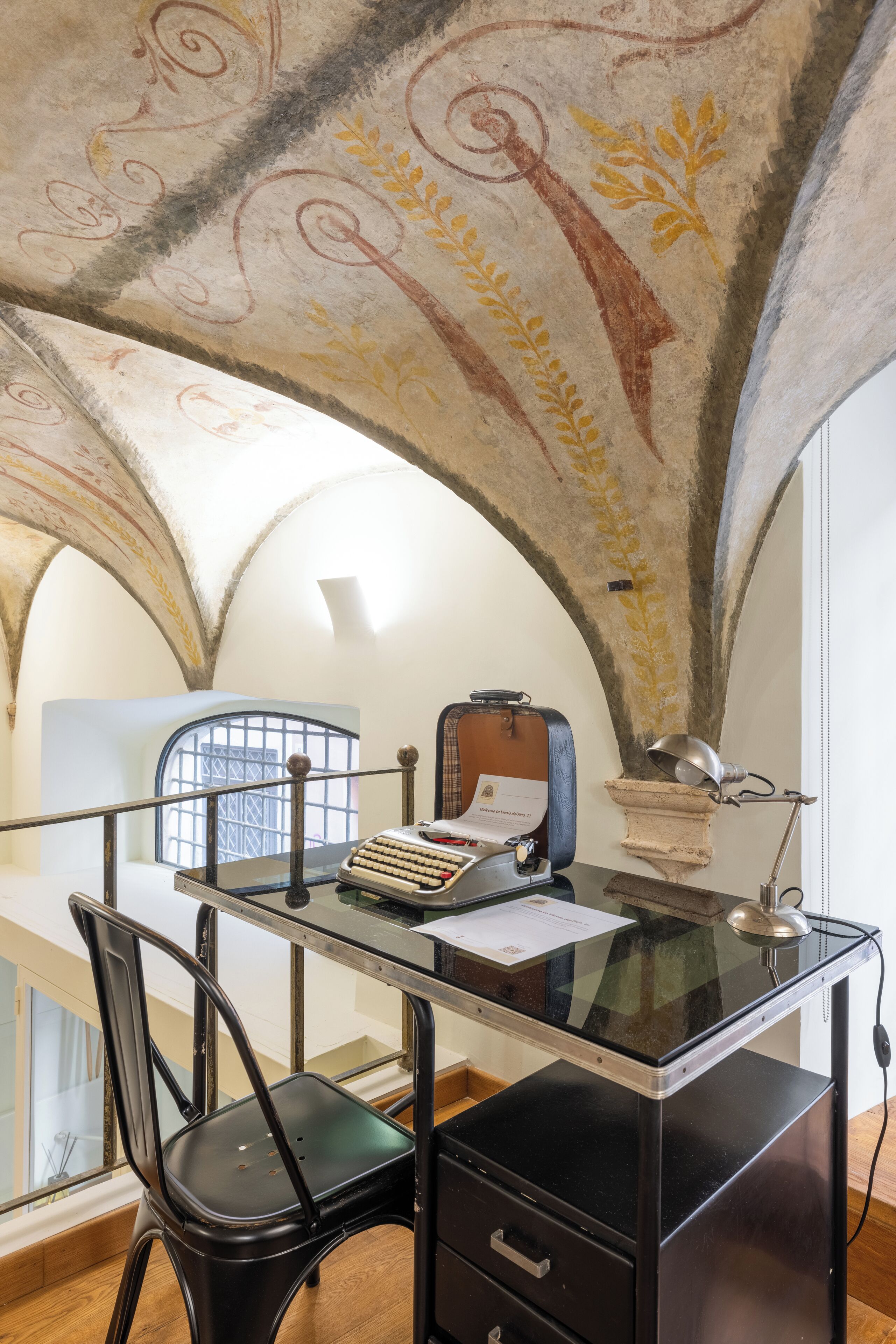 Quarto com escrivaninha, cadeira e teto com detalhes decorativos.