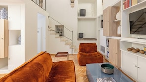 A modern living room with a staircase, a sofa, a coffee table, and a TV. - Piazza Navona - Apartment with Authentic Fresco of the 1500s (Roma)