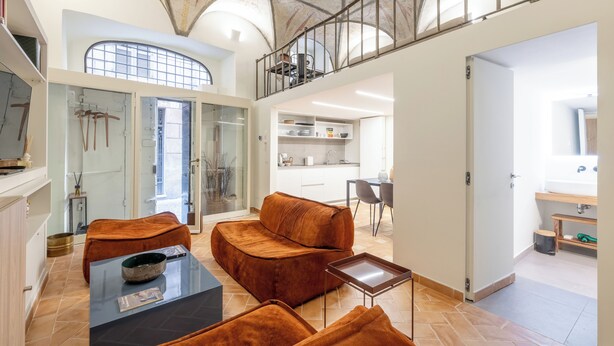 A spacious living area with a high ceiling, a glass door leading to a balcony, and a kitchen in the background. - Piazza Navona - Apartment with Authentic Fresco of the 1500s (Roma)
