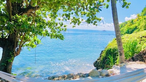 A hammock on a rocky beach with clear blue water and a distant boat. - Waterfront Luxury Tented Experience with Saltwater Infinity Pool & Beach - 2 Bed (Vigie)