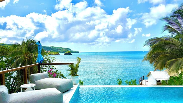 A pool area with a view of the sea and a distant island. - Waterfront Luxury Tented Experience with Saltwater Infinity Pool & Beach - 2 Bed (Vigie)