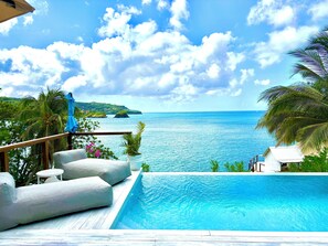 A pool area with a view of the sea and a distant island. - A Luxury Tented Experience with a Saltwater Infinity Pool and Private Beach. (Vigie)