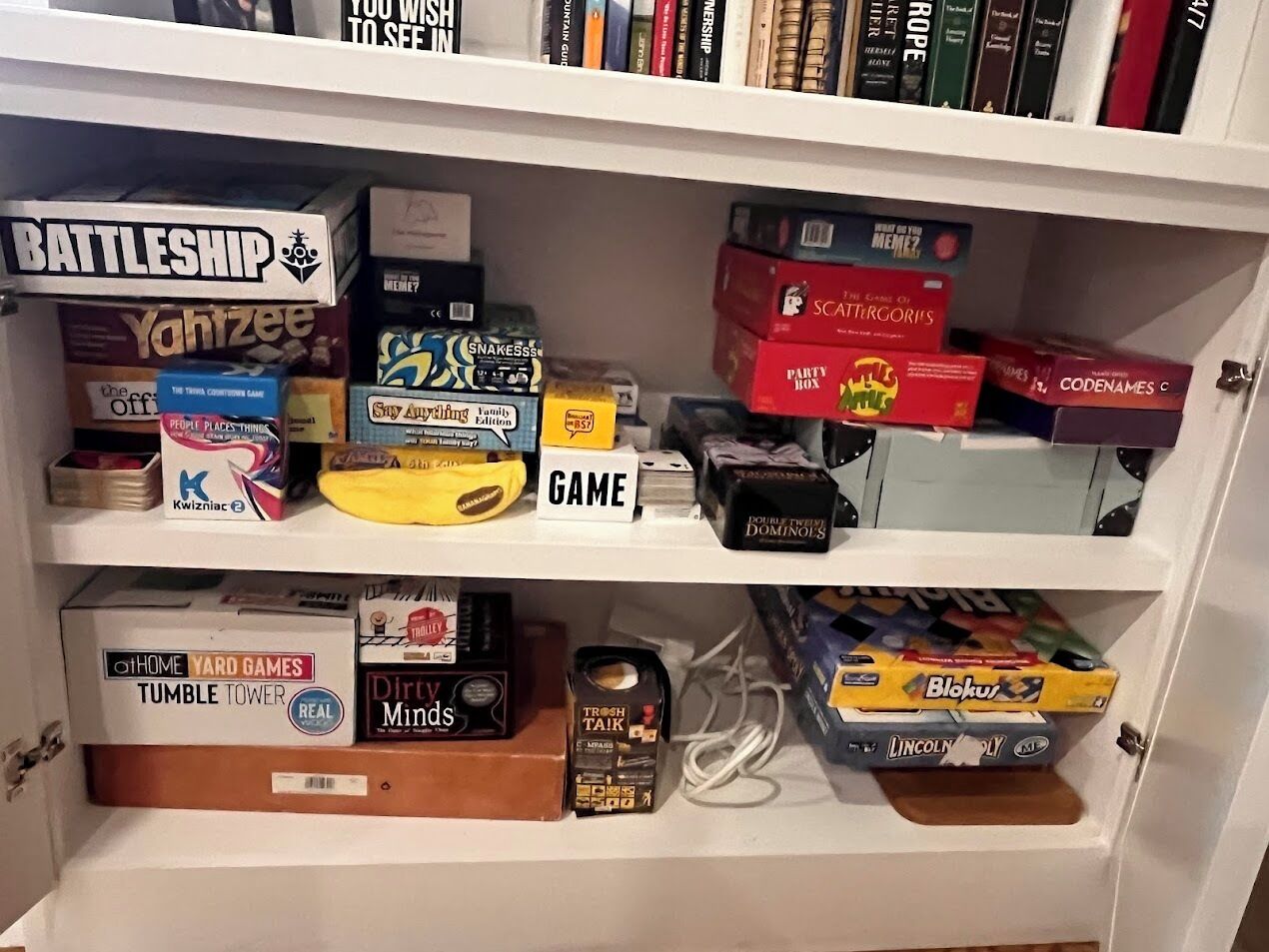 A bookshelf with various board games and books.