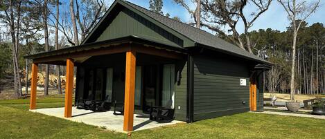 A lodge with a covered patio, outdoor seating, and a large window.