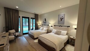 Habitación de hotel con dos camas, un escritorio y vistas al exterior.