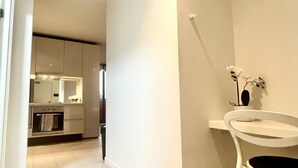 A modern kitchen with white cabinets, a built-in oven, and a white sink with a vase of flowers. - 2BR in Culture & Business Center (Melbourne)