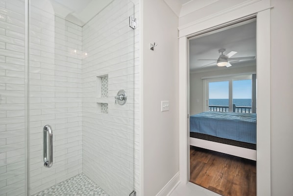 A bathroom with white subway tiles, a shower with a glass door, and a visible shower control. - Ollie's Point: Spectacular Oceanfront Home With Pool and Elevator (Oak Island)