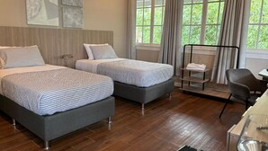 Une chambre d’hôtel avec deux lits, un bureau et une chaise.