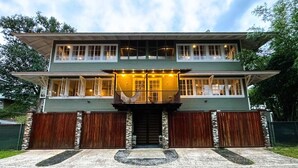 Une maison à deux étages avec un porche à l’avant, une clôture en bois et des fondations en pierre.