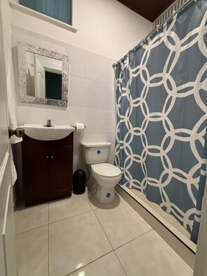 A bathroom with a white sink, a toilet, and a shower curtain with a geometric pattern. - Tropical House with Historic Charm, WiFi, Private Bathrooms and Workspaces (Panamá)