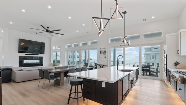 Una cocina moderna con una isla grande, taburetes de bar e iluminación colgante.