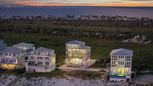Una propiedad costera con varias casas, una playa y vista al océano al anochecer.