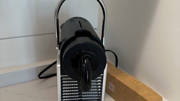 A black coffee maker on a white countertop with a cardboard box nearby.