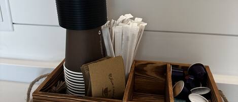 A wooden box labeled "Coffee Bar" containing a coffee maker, napkins, a card, and a cup.