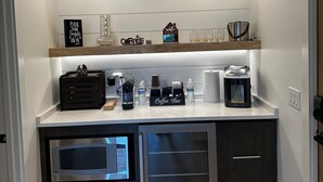 Eine kleine Küche mit einer Kaffeestation, zwei Pendelleuchten und einer Mikrowelle.
