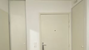 Una habitación con dos puertas blancas, suelo de madera y un interruptor de luz en la pared.