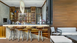 Un coin bar avec des étagères en bois, un attrape-rêves suspendu et un canapé blanc.