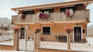 A two-story building with a balcony, a gate, and flower boxes. - AFFITTACAMERE MIRA SINNI  (Episcopia)