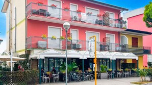 A two-story building with balconies, outdoor seating, and bicycles parked in front. - Holiday flat with balcony and air conditioning (San Michele al Tagliamento)