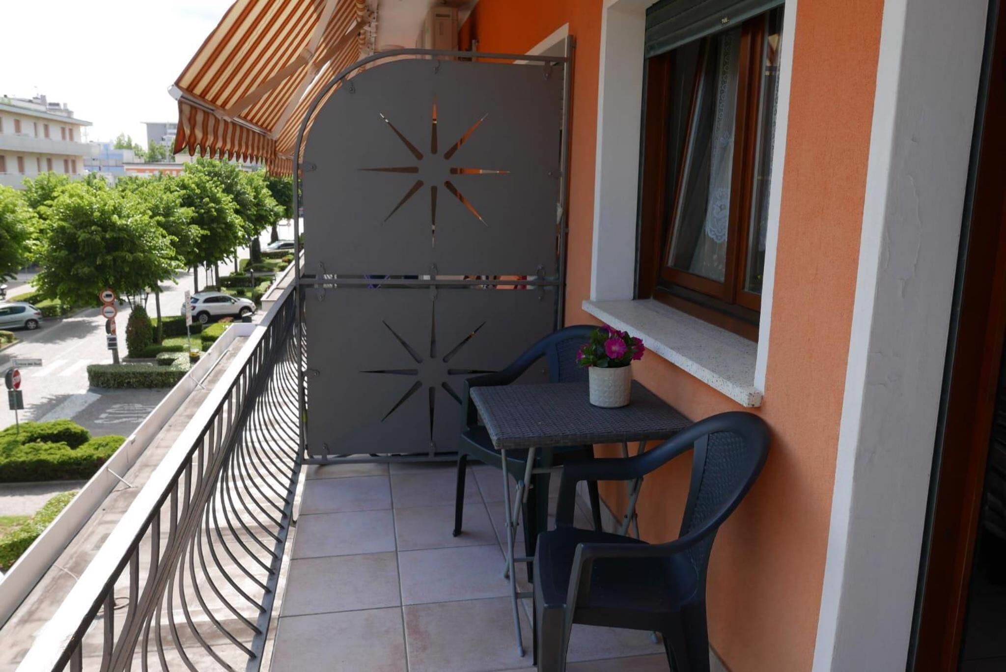 Un balcon avec une grille en métal, une petite table avec une chaise et une plante en pot.