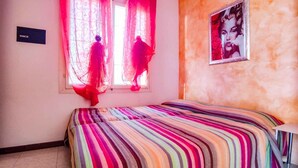 Une chambre à coucher avec un lit, une fenêtre ornée de rideaux légers et une affiche accrochée au mur.