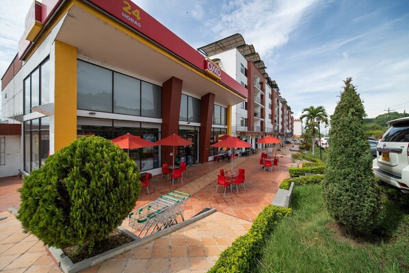 Ein Hotel mit Außenbestuhlung, roten Sonnenschirmen und einer gefliesten Terrasse.