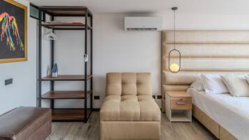 A modern bedroom with a sofa, a bed, a nightstand, a wardrobe, and an air conditioning unit.