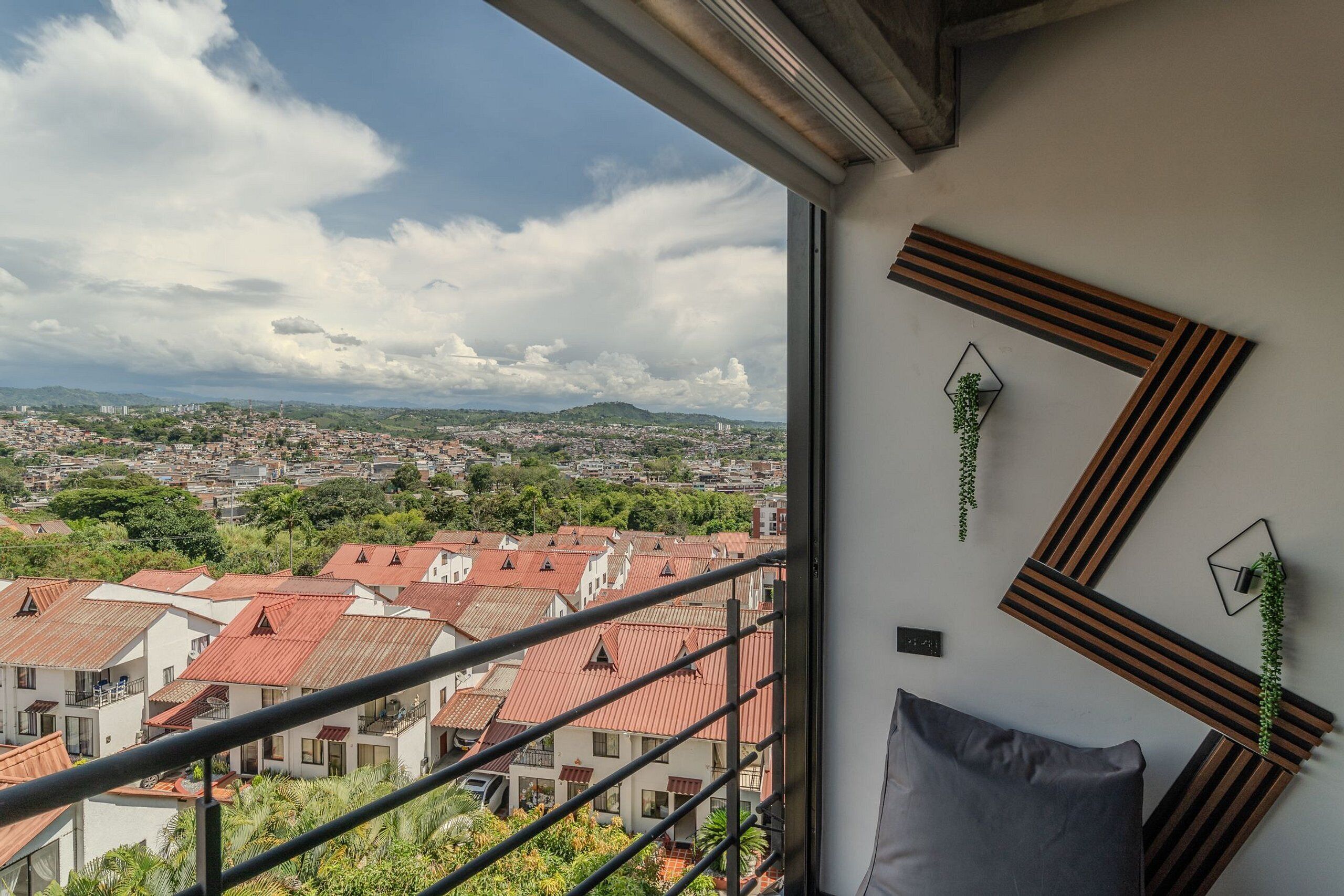 Un balcón con vista a la ciudad, un diseño moderno en la pared y una pequeña planta.