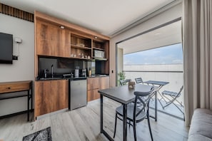 Eine moderne Küche mit Holzausstattung und Backofen, ein Essbereich mit Tisch und Stühlen sowie ein Balkon mit Blick zum Himmel.