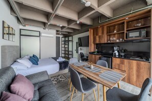 Een moderne, compacte woonruimte met een kitchenette, een eethoek en een slaapkamer.