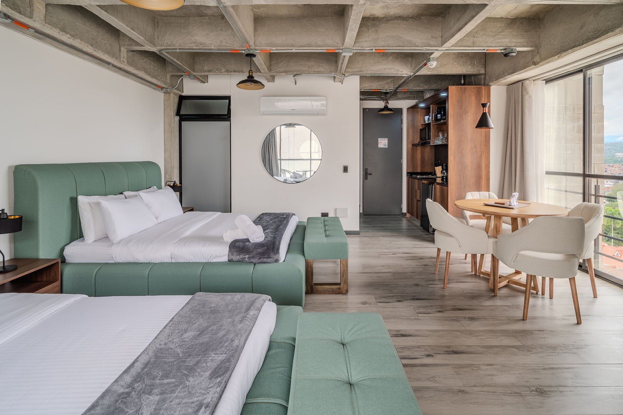 Ein modernes Hotelzimmer mit einem großen Bett, einem Essbereich und Blick auf die Stadt.