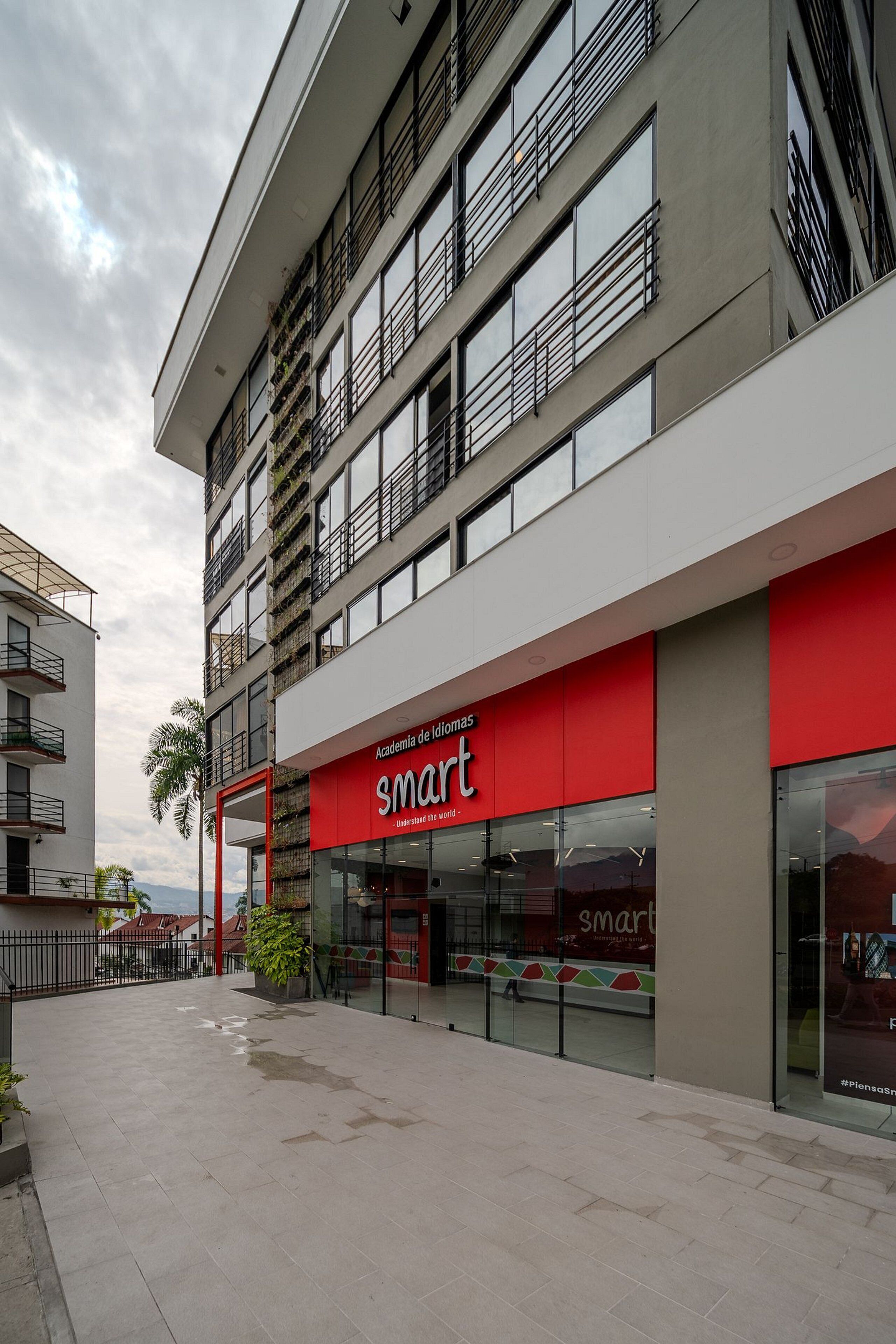 Un edificio moderno con fachada de vidrio y escaparate rojo con la palabra 'smart'.