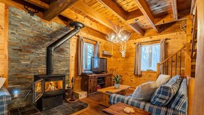 A cozy cabin interior with a fireplace, wooden walls, a sofa, and a television. - The Rustic - Nature retreat with Private SPA (Saint-Adolphe-d'Howard)