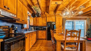 A wooden cabin interior with a kitchen, dining area, and a view of the outside. - The Rustic - Nature retreat with Private SPA (Saint-Adolphe-d'Howard)