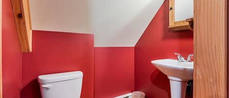 Ein kleines Badezimmer mit Toilette und Waschbecken, beide weiß, sowie ein Holzboden.