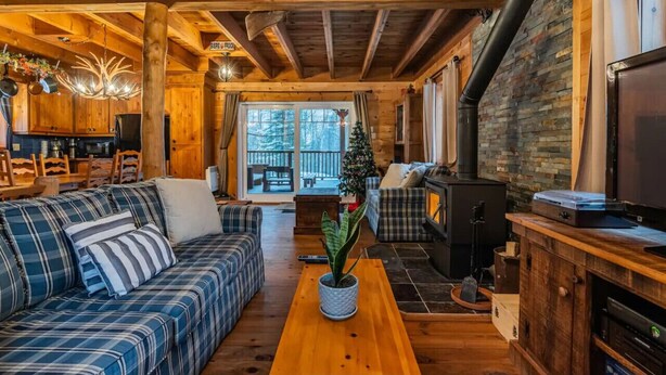 A cozy cabin interior with a wooden ceiling, a fireplace, a sofa, and a television. - The Rustic - Nature retreat with Private SPA (Saint-Adolphe-d'Howard)
