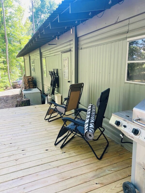 Eine überdachte Terrasse mit Gartenmöbeln und einem Grill.