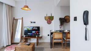Un soggiorno moderno con TV a schermo piatto, un'area pranzo con tavolo e sedie, una lampada a sospensione e un telefono fissato al muro.