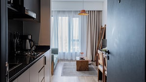 Una cucina moderna con una macchina da caffè, un'area pranzo con un tavolo e sedie in legno, e un'ampia finestra con tende leggere.