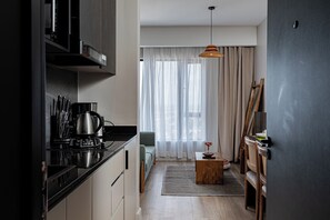 Une cuisine compacte dotée d’appareils électroménagers modernes, un coin repas avec une table en bois et une vue dégagée à travers des rideaux légers.