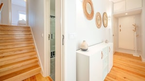 A modern interior with a wooden staircase, white walls, and a glass door leading to a bathroom. - GuestReady - A pinch of heaven in Lisbon (Lisbon)