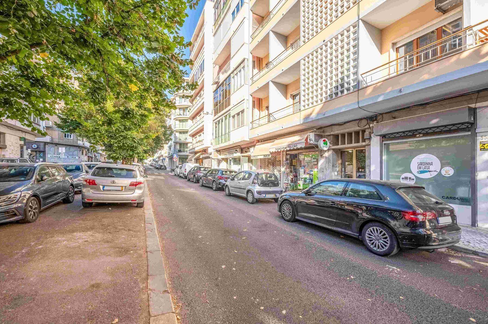 Une rue bordée de voitures garées et d’immeubles à plusieurs étages dotés de balcons.