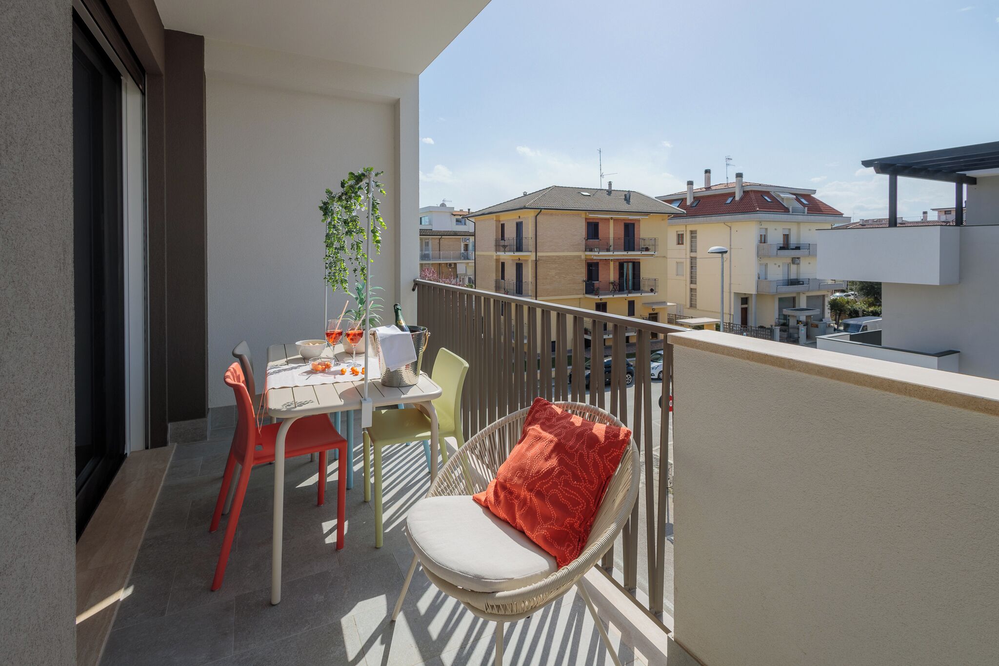 A balcony with a dining table, chairs, and a potted plant.