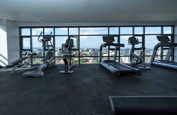 A gym with various exercise equipment, large windows, and a city view.