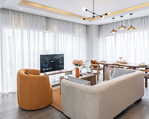 Un salon moderne avec un canapé, un fauteuil et un téléviseur à écran plat.