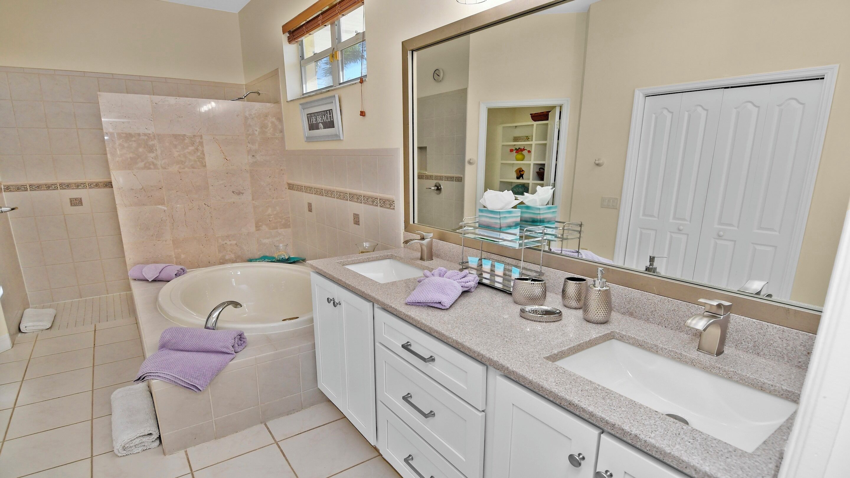 Une salle de bain avec une baignoire, deux lavabos, un grand miroir et une douche.