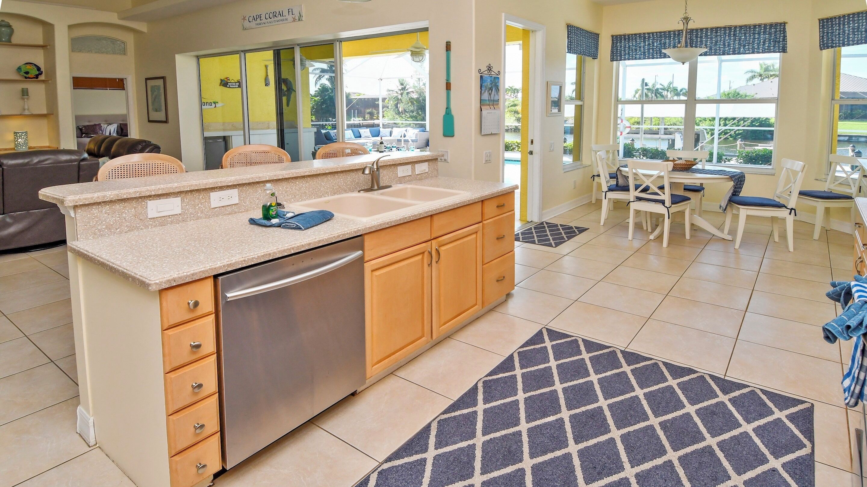 A kitchen with a dishwasher, a sink, and a dining area with chairs and a table.