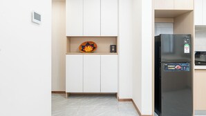 A compact kitchen with white cabinets, a black refrigerator, and a small shelf with decorative items. - 2 Bedroom - Spacious and Modern - Riverside One (Nairobi)