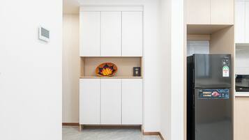 Una cocina compacta con armarios blancos, un refrigerador negro y una pequeña repisa con objetos decorativos.